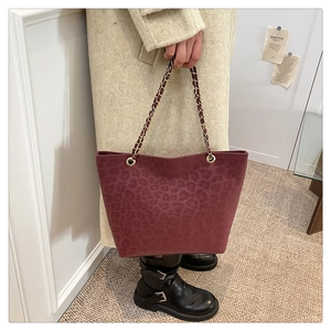 Detail of burgundy leopard print tote bag with gold chain strap and suede texture