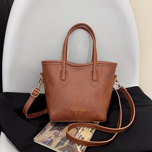 Sac seau en cuir marron avec poignées et bandoulière réglable sur une chaise