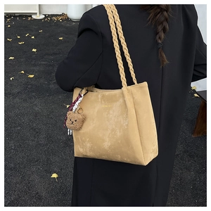 Detail of apricot matte leather tote bag with woven straps and cute bear charm pendant