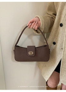 Detail of a brown retro baguette bag with golden horsebit buckle and suede texture