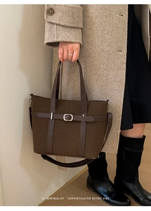 Detail of dark brown tote bag with textured fabric, leather strap, and silver buckle closure