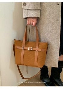 Detail view of mustard yellow woven tote bag featuring retro leather straps and metal buckles