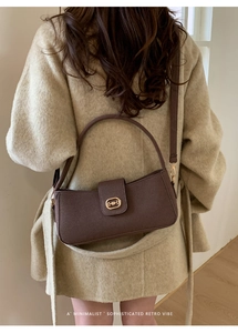 Detail of brown faux leather underarm bag featuring a vintage golden horsebit buckle