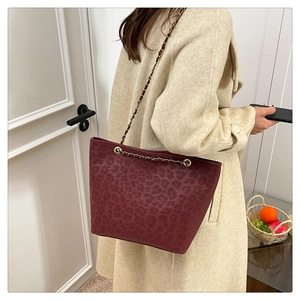 Detail view of burgundy leopard print tote bag with metal chain and leather strap