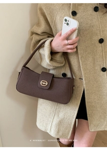 Close-up of a retro brown shoulder bag featuring a gold horsebit metal buckle detail