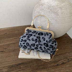 Vintage leopard shell handbag with gold handle and chain strap on a rustic table