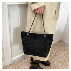 Detailed view of leopard print tote bag with gold chain strap on beige coat