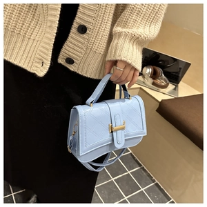 Gros plan d'un petit sac bleu ciel matelassé avec poignée et fermoir métallique chic