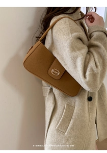 Detail of caramel brown suede texture bag with a vintage oval gold metallic buckle