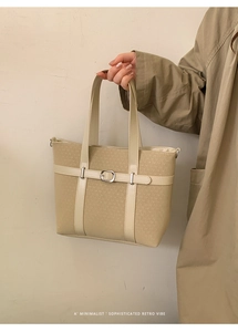 Close-up of beige woven tote bag with faux leather trim and silver buckle detailing