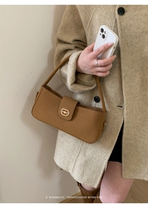Close-up of brown suede baguette bag featuring a vintage gold horsebit buckle detail