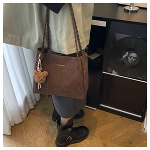 Detail of dark brown matte tote bag featuring woven strap and fashion text engraving
