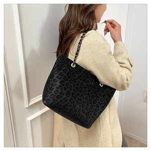 Close-up of leopard print tote bag with gold metal chain strap on model shoulder