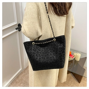 Detail of leopard print suede tote bag featuring a metal and leather chain shoulder strap