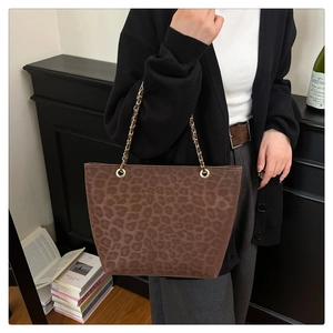 Detail of leopard print tote bag with gold chain strap shown on a side table