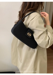 Detail of minimalist black underarm bag with gold horsebit buckle and fabric texture