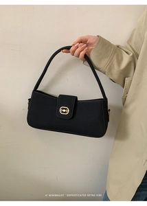 Detail of minimalist black baguette bag with gold horsebit hardware and smooth texture