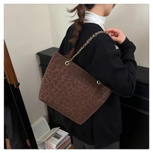 Detail of leopard print tote bag with gold chain strap on model's shoulder in winter