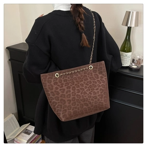 Detail of leopard print tote bag featuring elegant golden metal chain strap on shoulder
