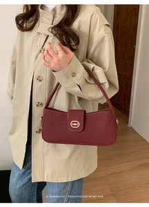 Detailed view of vintage burgundy square bag with gold horsebit buckle on beige coat