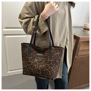 Detail of leopard print tote bag with black leather label and fashion text embroidery