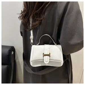 Close-up of white quilted leather crossbody bag with golden H-clasp and adjustable strap