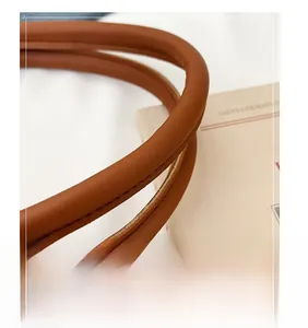 Detailed close-up of comfortable brown matte tote handles with precise stitching detail