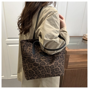 Detail der trendigen Tragetasche mit Leopardenmuster, Fashion-Label und schwarzen Griffen