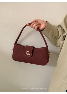 Detail of dark red suede baguette bag featuring a gold vintage horsebit buckle design
