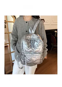 Detail of silver puffy quilted backpack with high-shine metallic finish and braided zippers