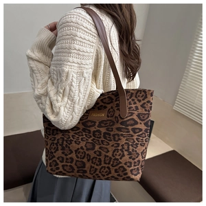 Detailansicht der Tragetasche mit Leopardenmuster und braunen Ledergriffen am Modell
