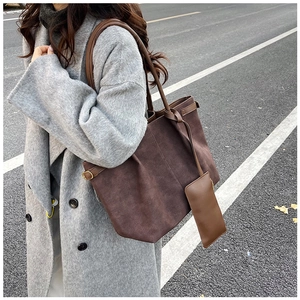 Detail shot of a large brown matte tote bag featuring a matching pouch and side metal buckles