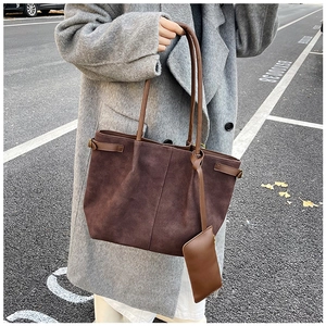 Detail of dark brown suede tote bag with slim straps and matching mini coin purse accessory