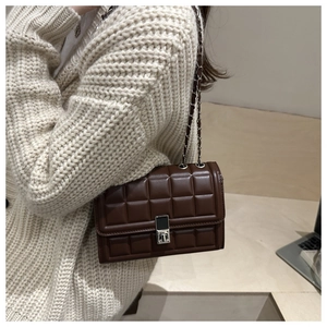 Close-up of quilted dark brown crossbody bag with silver square lock and chain strap