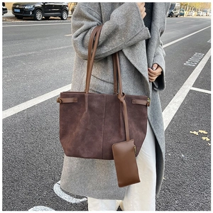 Detail of a large brown suede tote bag with a small matching pouch and shoulder strap