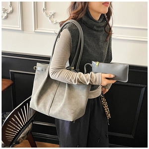Detail of grey suede tote bag with matching inner pouch on model in a modern room