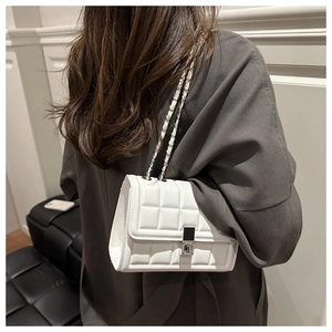 Close-up of white quilted leather chain bag with silver buckle worn on model shoulder