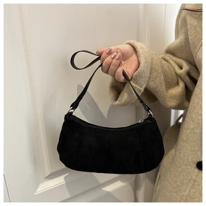 Détail du sac baguette minimaliste en daim noir montrant la texture fine et la bandoulière