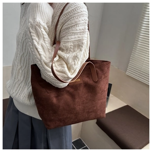 Detail of dark brown suede tote bag with leather FASHION label and slim shoulder straps