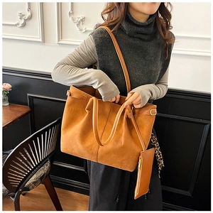 Detailed view of caramel suede tote bag with matching zippered pouch on a vintage chair