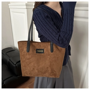 Detail shot of brown frosted leather tote bag featuring a black fashion label and slim strap