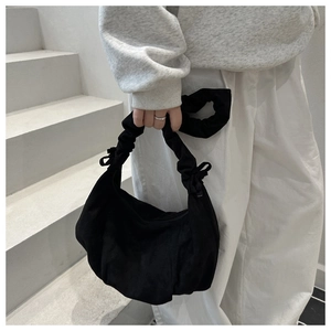 Close-up of black suede underarm bag with pleated cloud-style handle and soft texture