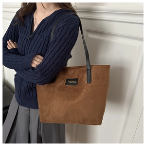 Close-up of caramel brown tote bag with matte texture and gold FASHION label detail