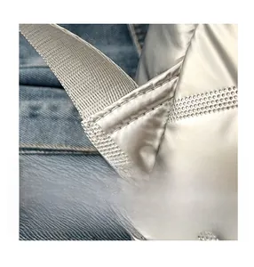 Macro shot of reinforced stitching on a silver quilted backpack with metal texture