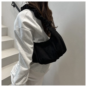 Vue latérale d'une femme portant un sac hobo plissé noir dans un intérieur minimaliste