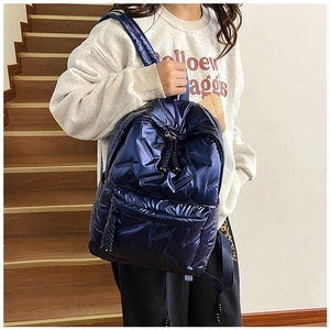 Detail of dark blue quilted backpack with shiny metallic finish and front zipper pocket