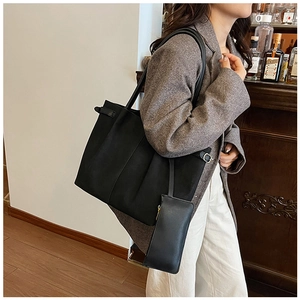 Side view of a black matte leather tote bag with a small matching zipper pouch attachment