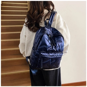 Rear view of a model wearing the dark blue quilted puffer backpack on indoor stairs