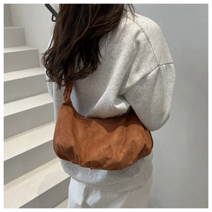 Detail of a brown suede hobo bag with drawstring pleats and minimalist crescent shape