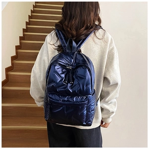 Close-up of shiny navy blue quilted backpack with padded straps and metallic finish